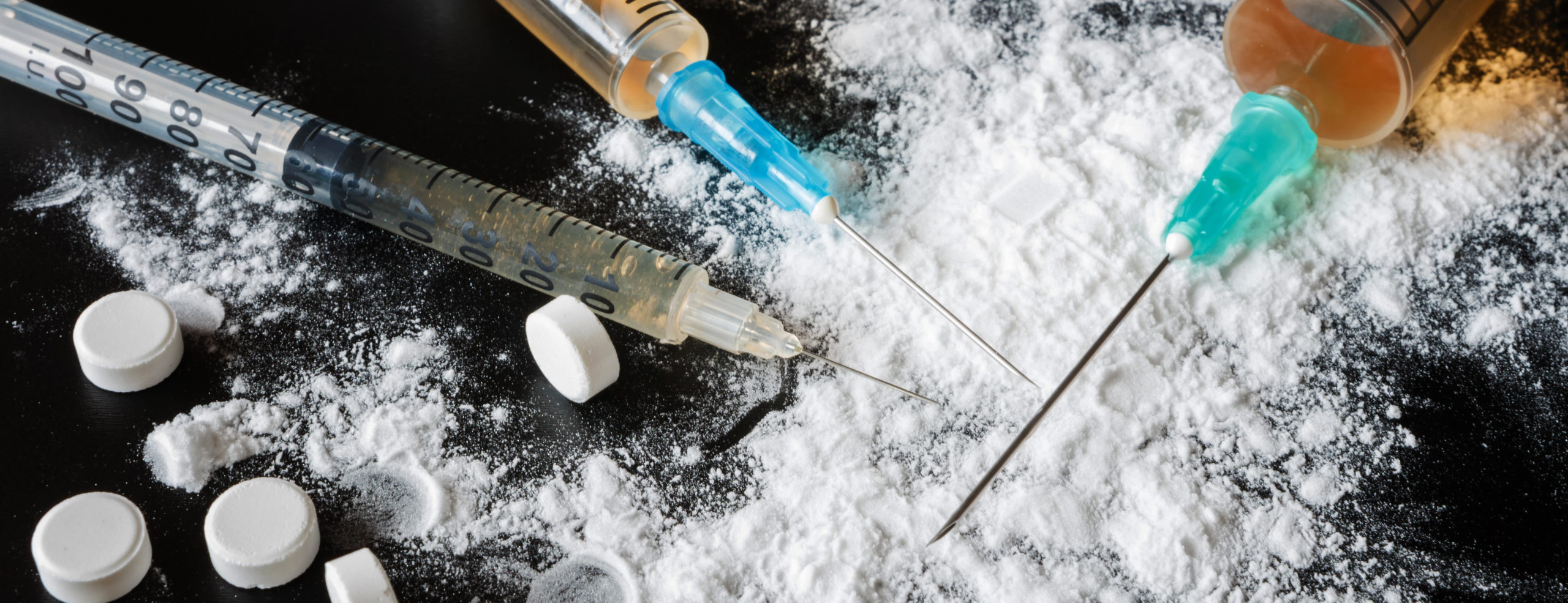 Drugs heroin powder pills and syringes on a black background fla