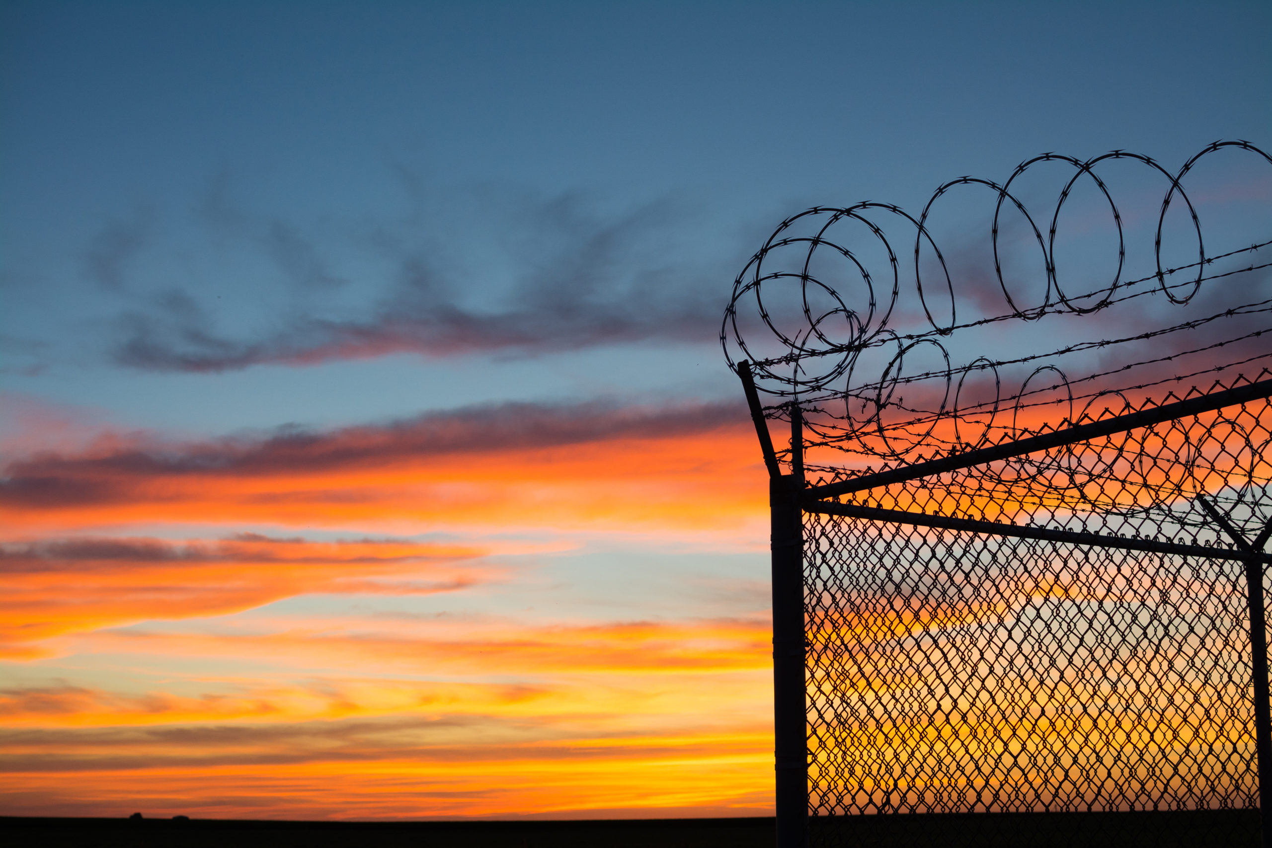 BSilouette of fence at sunset