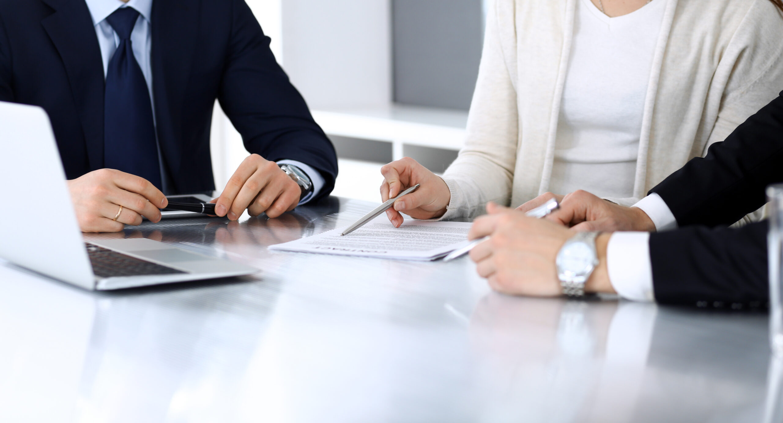 Business people discussing contract working together at meeting at the glass desk in modern office. Unknown businessman and woman with colleagues or lawyers at negotiation. Teamwork and partnership concept