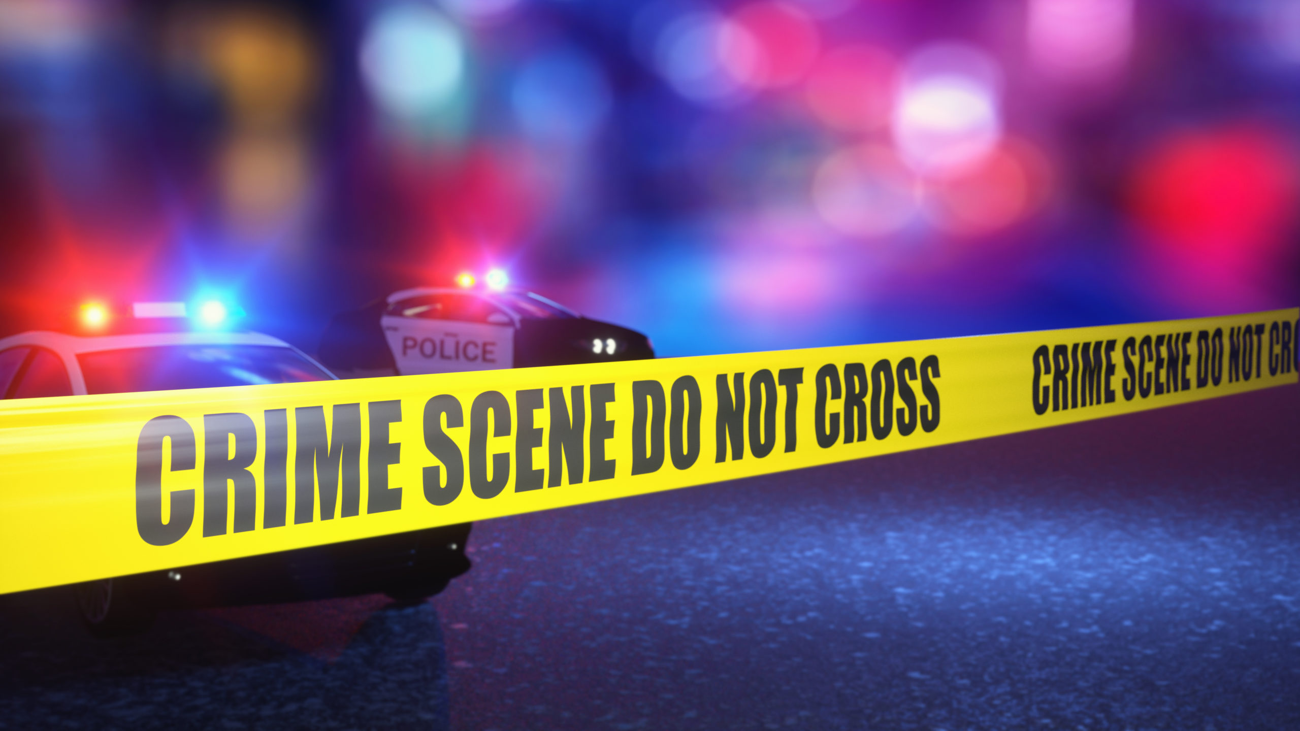 Crime scene with crime scene tape and blurred policed car in bac
