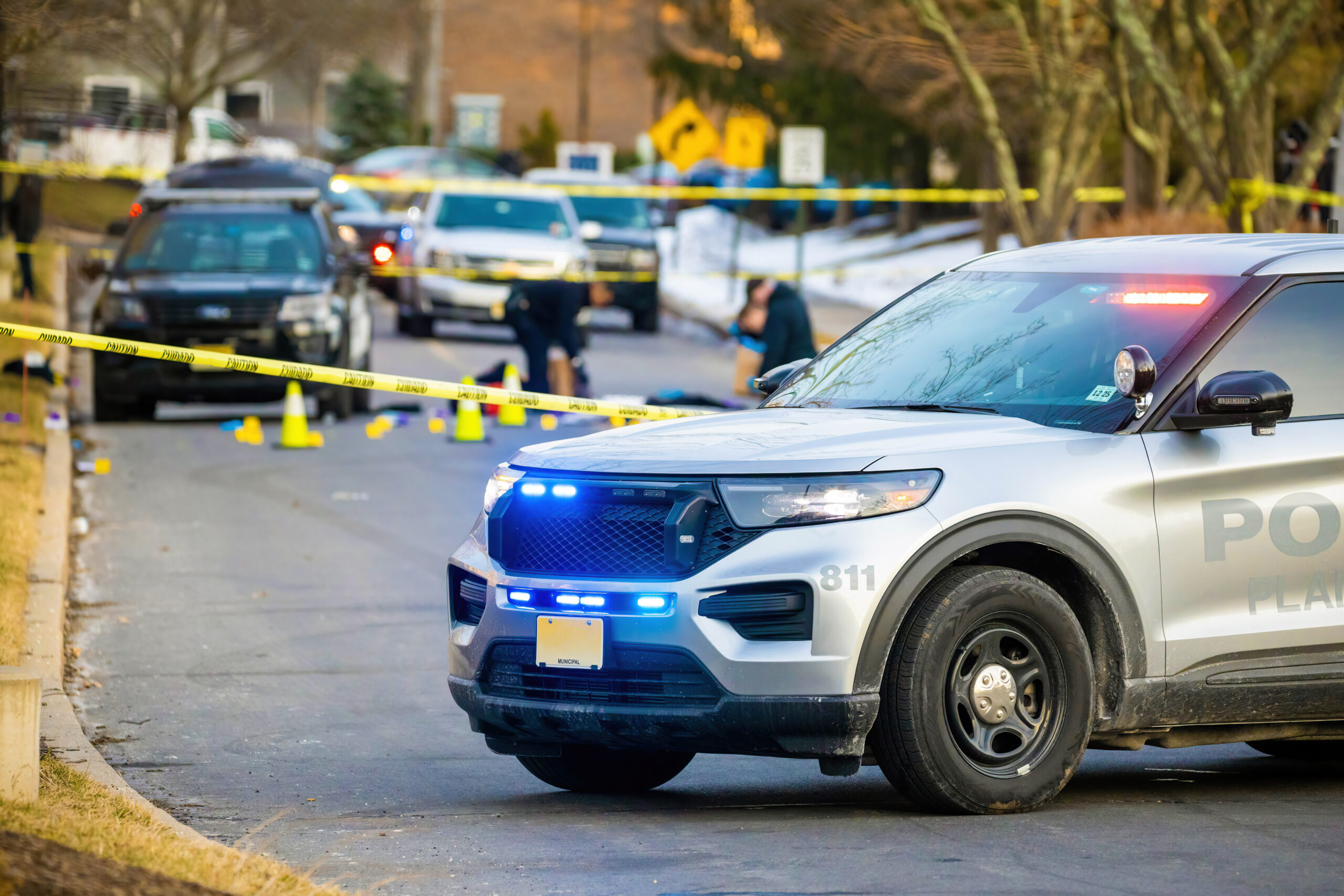 Police car with emergency lights on road with caution tape